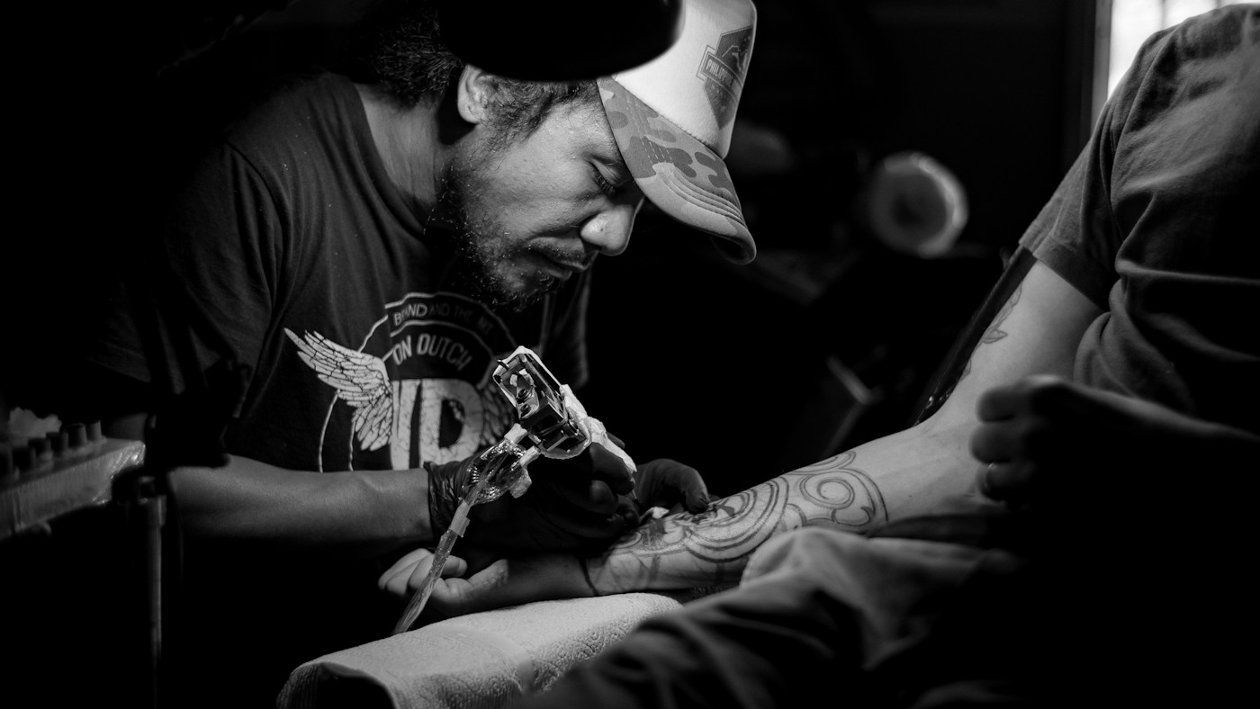 Pormenor do trabalho de um tatuador, concentrado no desenho sobre a pele